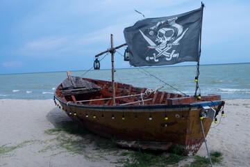 Wooden fishing boats by the sea with pirate flags adorned.