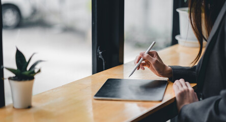 Businesswoman hand working with stylus pen on digital tablet at coffee shop cafe