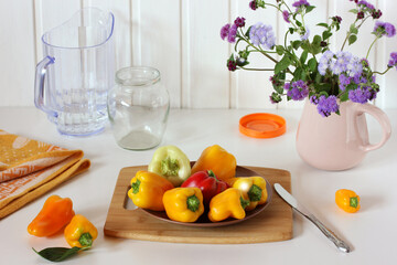 ripe bell peppers and a bouquet of ageratum in a jug