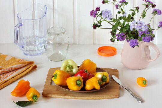 Ripe Bell Peppers And A Bouquet Of Ageratum In A Jug