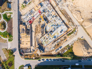 Residential building under construction. Cranes and other construction machinery surrounds a new building being built in a green neighborhood.