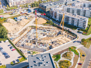 aerial top view of new modern apartment building under construction. yellow cranes working at construction site