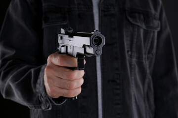 Man holding gun on black background, closeup