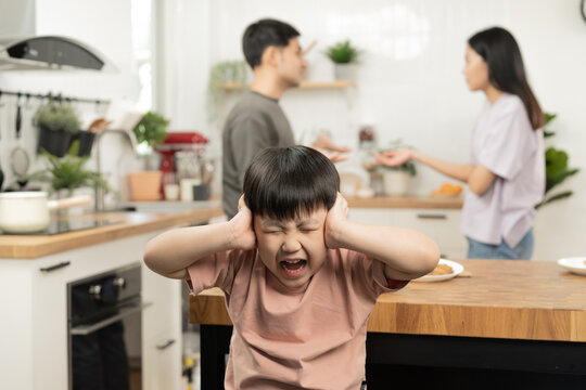 Little Asian Sad Boy, Unhappy While Parents Fighting, Kid Son Not Listen To Shouting Noise While Mom And Dad Arguing, Quarrel Behind. Family Suffering, Stressed. Violence And Divorce Couple Concept.