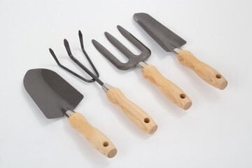 Small shovels and rakes with wooden handles, gardening tool isolated on white background