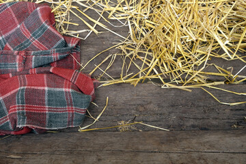 Plaid and straw on wooden boarded surface.