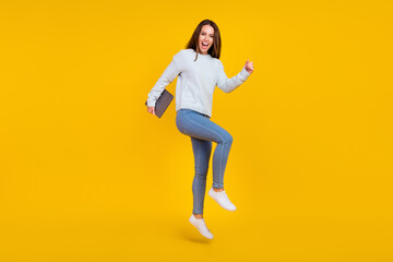 Fototapeta na wymiar Full length photo of happy cheerful lady hold laptop jump winner good mood isolated on yellow color background
