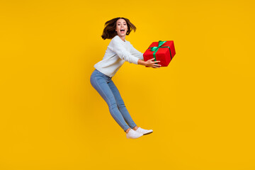 Full body photo of amazed positive young woman jump up gift celebrate get isolated on yellow color background