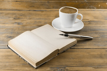 Open a blank page book, pen and cup of coffee on the desk