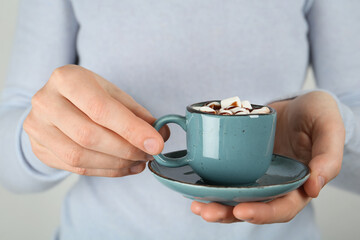 Woman holding cup of delicious hot chocolate with marshmallows and syrup, closeup