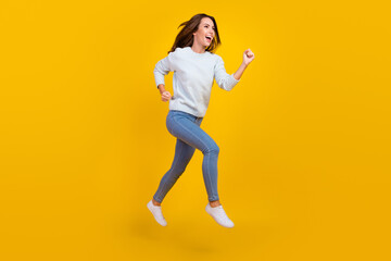Fototapeta na wymiar Full body photo of cheerful dreamy young woman jump up run sale empty space isolated on yellow color background