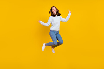 Fototapeta na wymiar Full size photo of cheerful positive cool young woman jump up make v-signs sale isolated on yellow color background