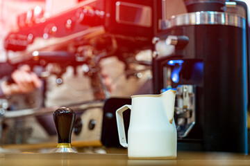 Coffee latte art in coffee shop. Special jug standing at the bar counter and preparing for pouring...