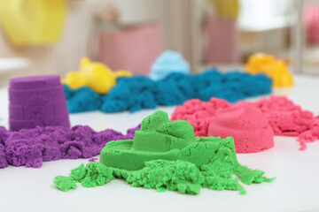 Colorful kinetic sand on white table indoors