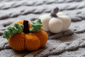 Knitted pumpkin on knitted cover, cozy home background, close-up 