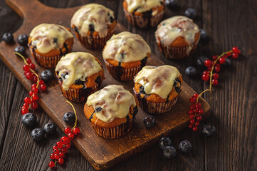 Homemade muffins with red currants and blueberry, covered with white chocolate topping.