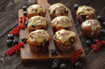 Homemade muffins with red currants and blueberry, covered with white chocolate topping.