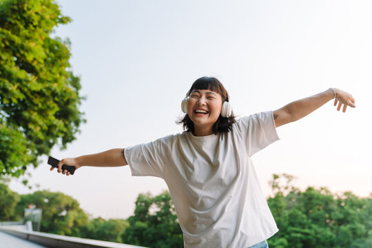 Smiling Young Asian Woman Walking In A Green Park