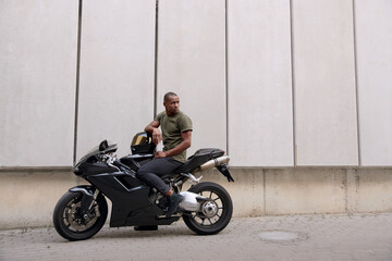 Obraz na płótnie Canvas Young black man sitting on sports motorcycle