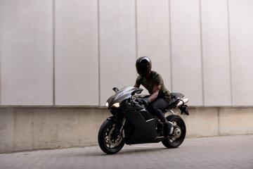 Fototapeta na wymiar Black motorcycle biker in helmet on city street
