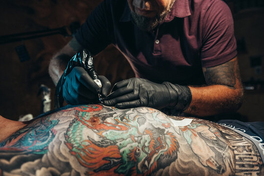 Tattoo artist hands wearing black gloves and holding a tattoo machine