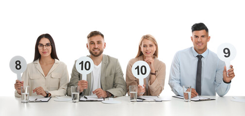 Panel of judges holding different score signs at table on white background