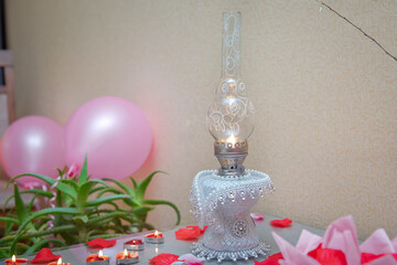Vintage kerosene lamp on table .vintage kerosene oil lantern lamp burning with a soft glow light in an antique rustic country barn with aged wood floor . Kerosene lamp on rustic table.