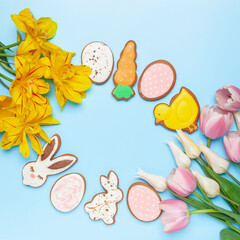 Glazed color gingerbread Easter figures - rabbit, chicken, egg, carrot  and tulips flowers on a blue background. Happy Easter. Top View