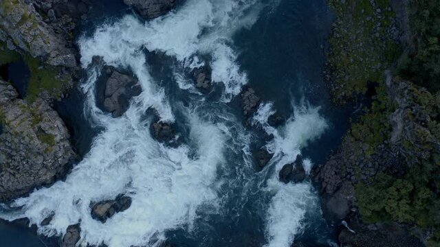 Pedestal shoot of a waterfall cascading by cliffs.