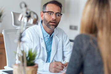 Shot of handsome mature male doctor talking while explaining medical treatment to patient in the...