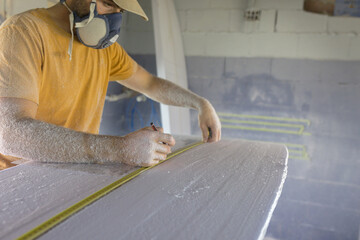 Surfboard shaper measuring board distance in Workshop