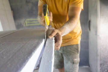 Surfboard making, woodworker wearing safety respirator sawing surfboard blank using handsaw