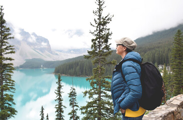 Woman with backpack looking at turqouise lake and mountains