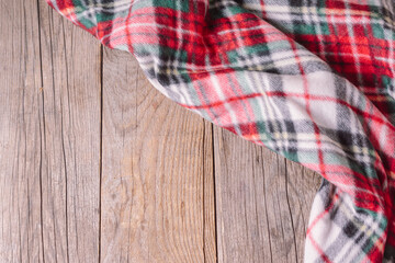 Red plaid on wooden background. Space for text. Christmas or Thanksgiving frame