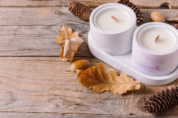 Two natural soy candles on wooden background. Scented candles for interior. Cozy autumn