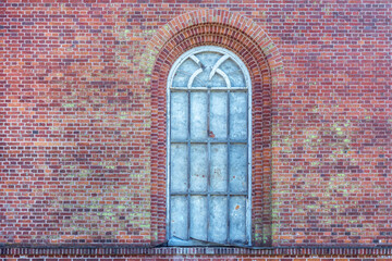 Arched window opening with an old wooden frame on the background of an old red brick wall. From the Windows of the world series.