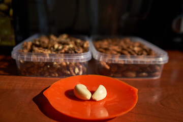 Peace of garlic. Nuts in the background. 