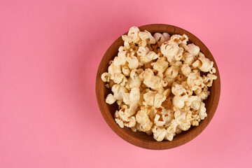 top view wooden bowl with sweet popcorn on pink background with copy space