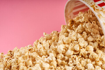 popcorn falling from popcorn bucket on pink background