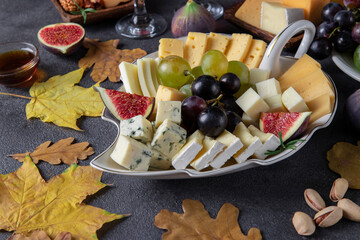 Variety of cheese and fruits on dark gray table. Appetizer for Thanksgiving Day.