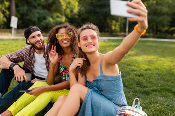 Obraz premium happy young company of friends sitting park