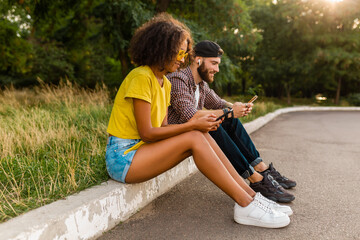 happy young smiling friends sitting park using smartphones