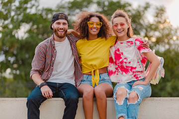 happy young company of smiling friends sitting in park