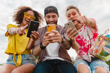 happy young company of smiling friends sitting in park