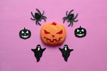 pumpkin on a pink background with ghosts. A place to copy. Flat lay. Interior decoration for the Halloween holiday. Selective focus