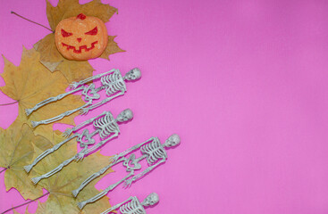 Orange pumpkin, skeletons, yellow dry leaves, black pumpkins. A place to copy. Flat lay. Interior decoration for the Halloween holiday. Selective focus