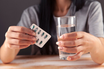 Close up cropped image millennial mixed race girl holding pill and glass of fresh water,