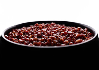 A lot of beautiful red pomegranate seeds in a black bowl