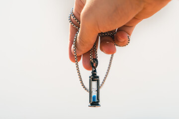 Man hand with a sand clock necklace