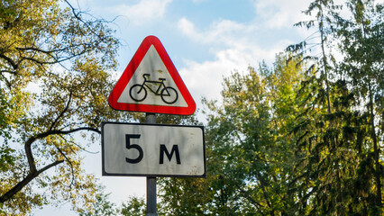 Bike traffic road sign. A red and white triangular road sign warns of cycling that can cross the road.